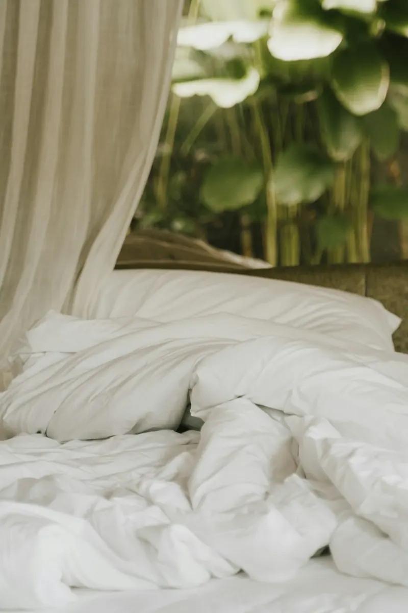 Cama de villa con sábanas blancas y palmeras